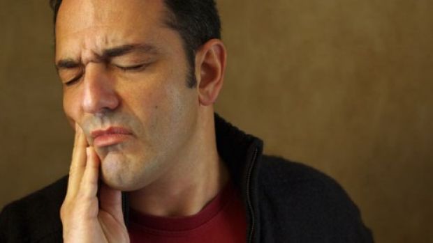 Photo of a man in discomfort holding his jaw